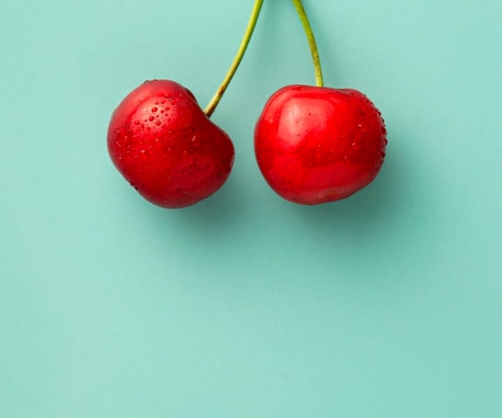 Wet cherries next to the cyan background