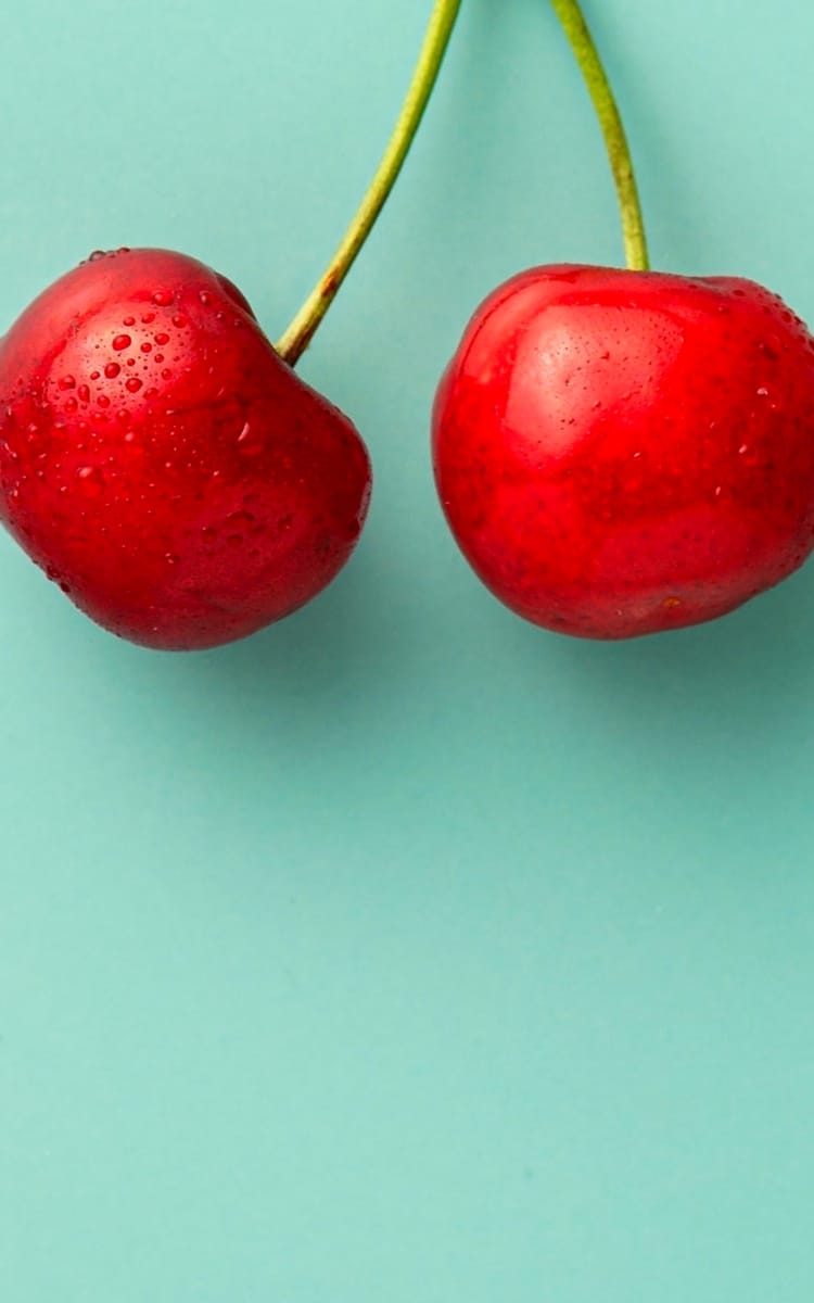 Wet cherries next to the cyan background